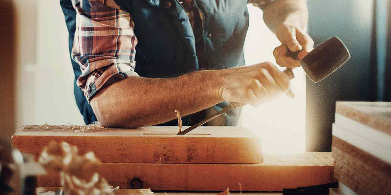 Handwerker verwendet Presch Handwerkzeuge beim Holzarbeiten mit Hammer und Meißel